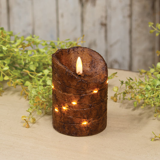 Decorative candle with a rustic design on a wooden surface with greenery