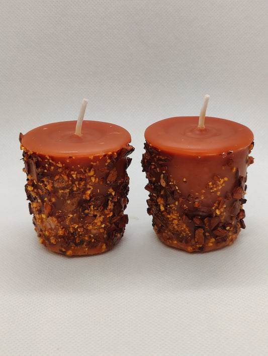 Two rustic candles with textured bases on a plain background