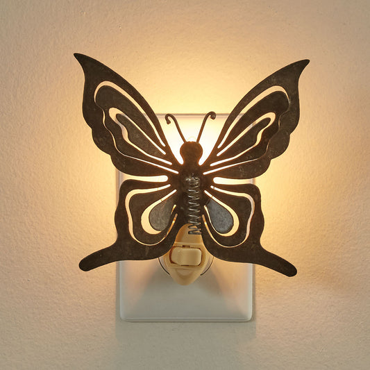 A brown butterfly-shaped nightlight mounted on a white wall, illuminated with a warm light.