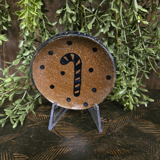 Decorative pottery with a candy cane design on a wooden surface with greenery