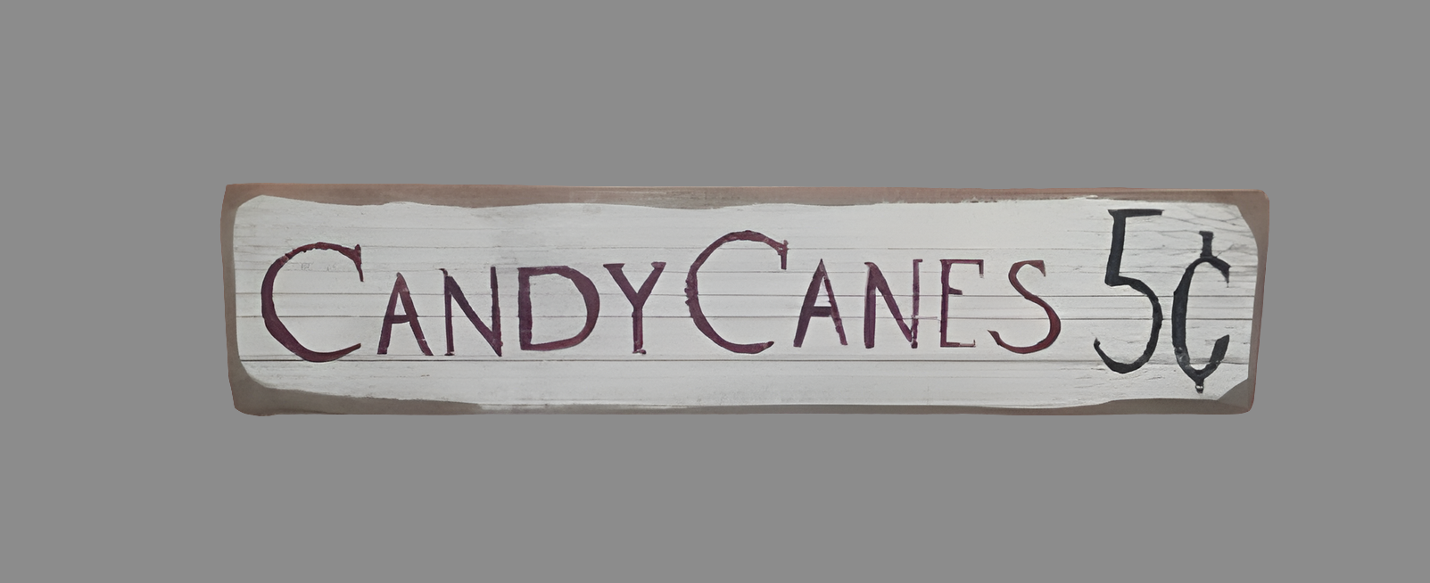 A wooden sign with the text 'Candy Canes 5 Cents' written in a rustic style.