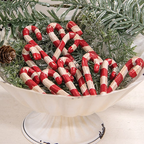 Decorative candy canes in a white dish with Christmas tree branches in the background