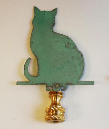 A green copper lamp finial in the shape of a cat, with a verdigris finish.
