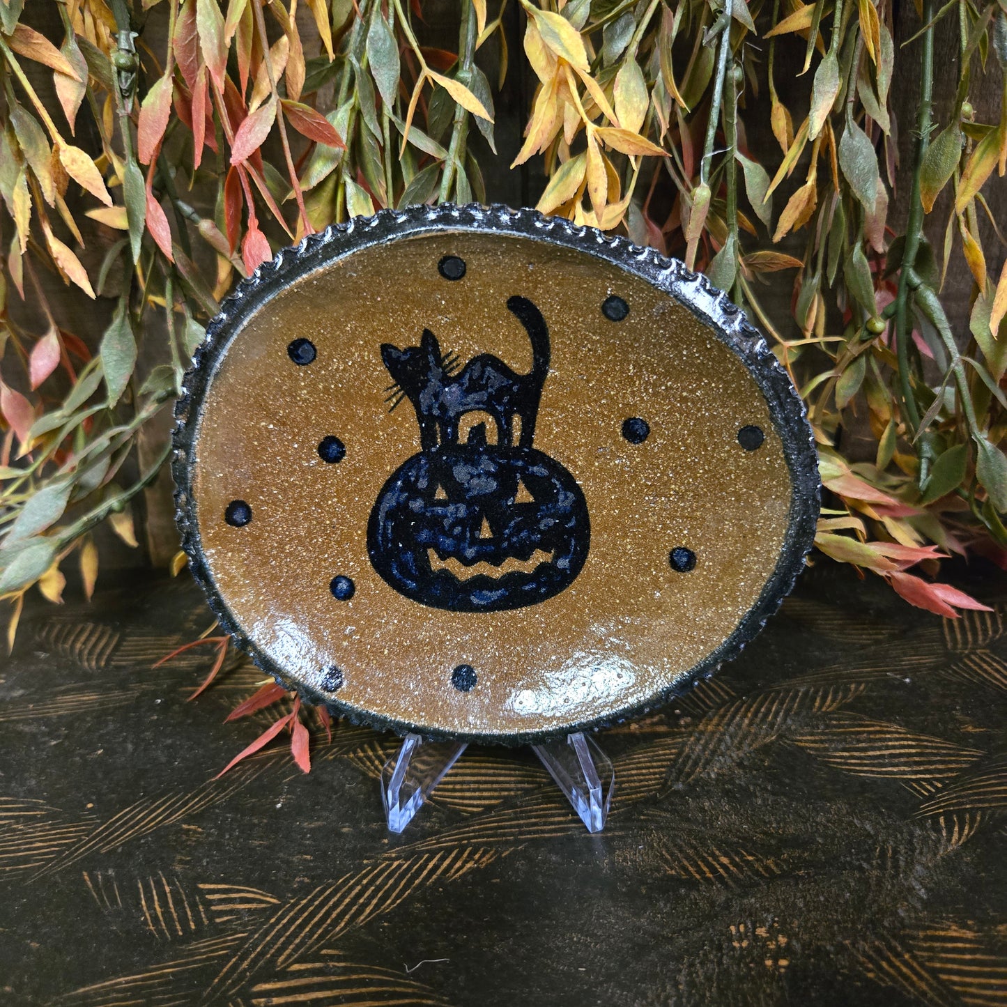 Decorative pottery with a black cat design surrounded by leaves.