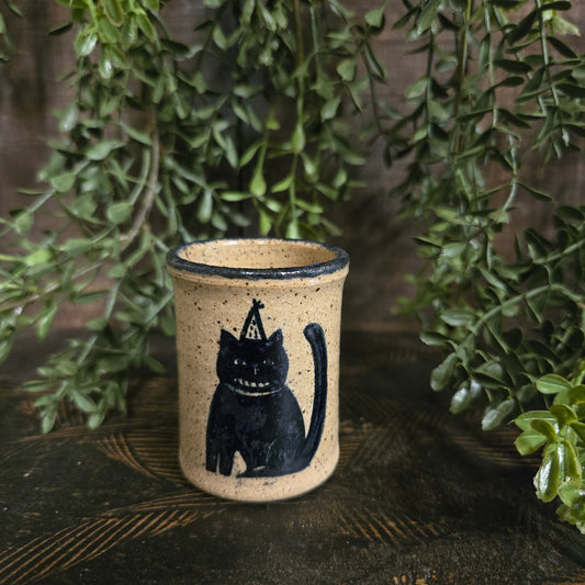 Miniature stoneware crock with a cat wearing a witch's hat and a Cheshire smile