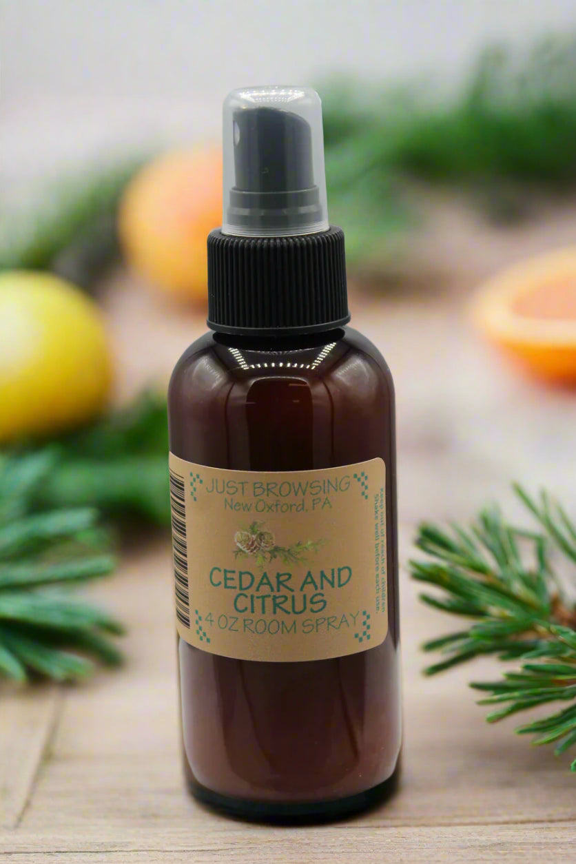Bottle of Cedar and Citrus room spray with a label on a gray background with sprigs of cedar and oranges.