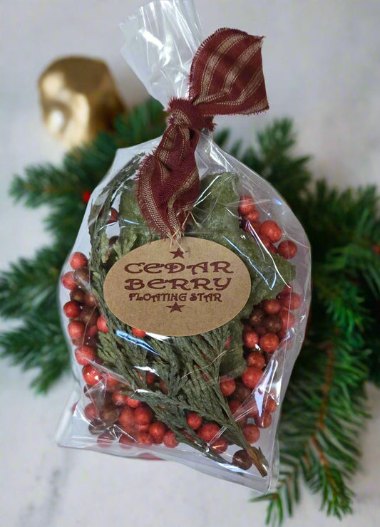 A small kit of cedar berry floating candles, packaged in clear plastic with a red ribbon and a label that reads 'Cedar Berry Floating Star'.