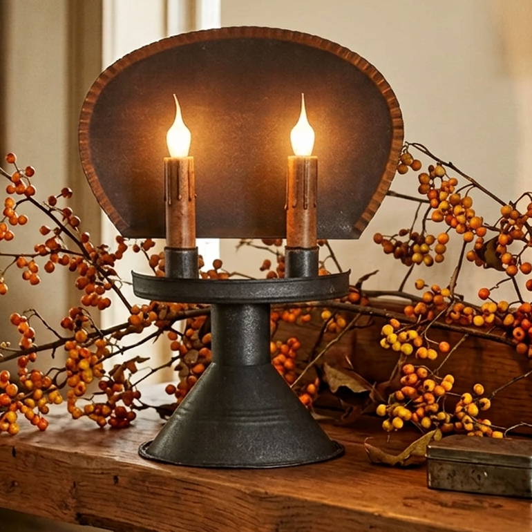 A Chesapeake Tin Table Light with two lit candles on a wooden surface, showcasing its sleek design and black color.