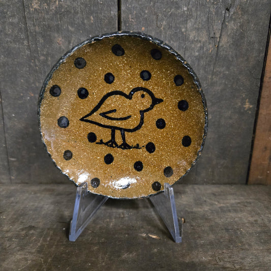 Round ceramic dish with black polka dots and a bird design on a wooden surface