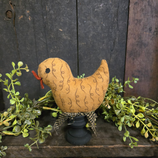Decorative moon-shaped plush toy with a face, surrounded by greenery on a wooden background