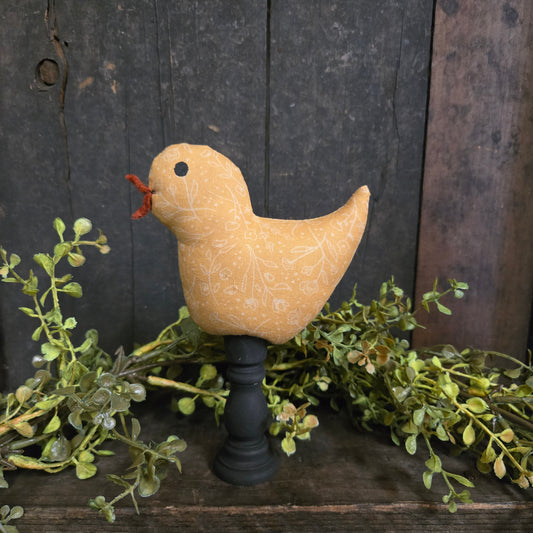 Decorative bird ornament on a wooden surface with greenery