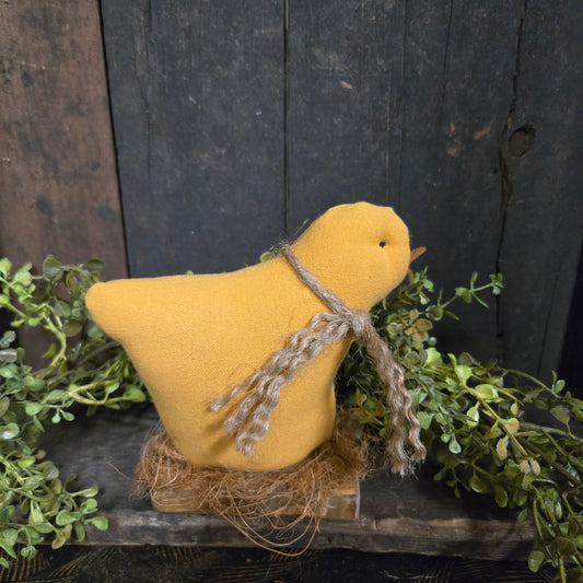Yellow fabric chicken with twine on a rustic wooden background