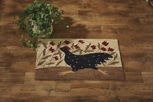 A rectangular hooked rug with a chicken design, floral patterns, and stars, placed on a wooden floor next to a potted plant.