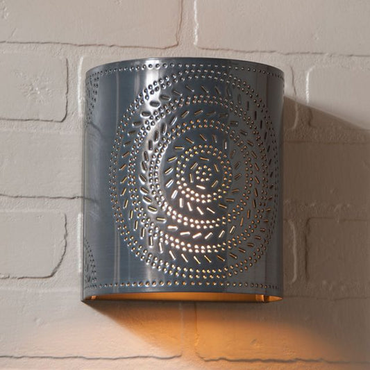 Decorative wall sconce with intricate cut-out design on a brick wall.