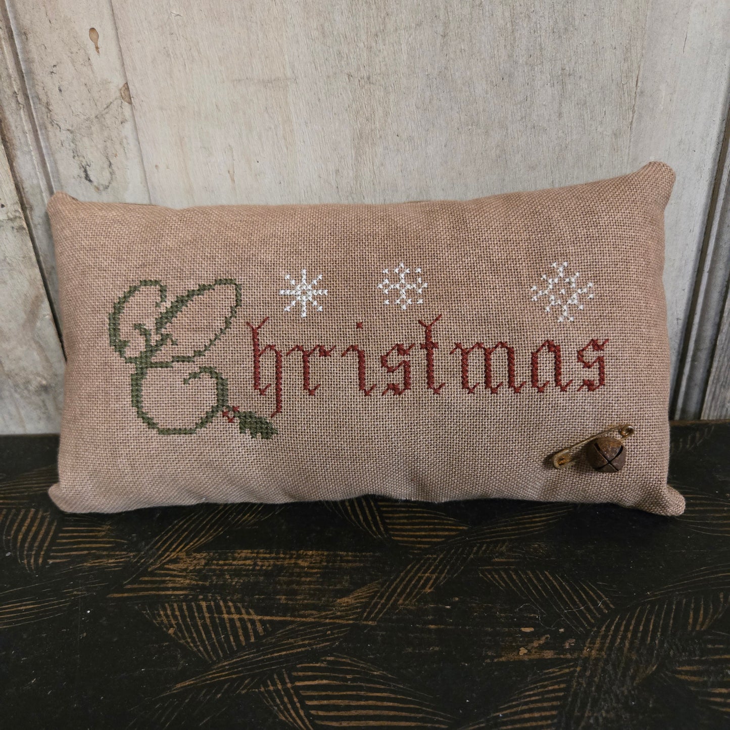 Decorative pillow with embroidered text and designs on a wooden surface