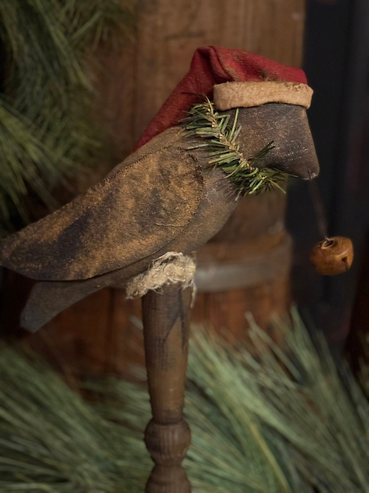 Decorative boot with a red top and greenery, placed on a wooden stand with a blurred background.