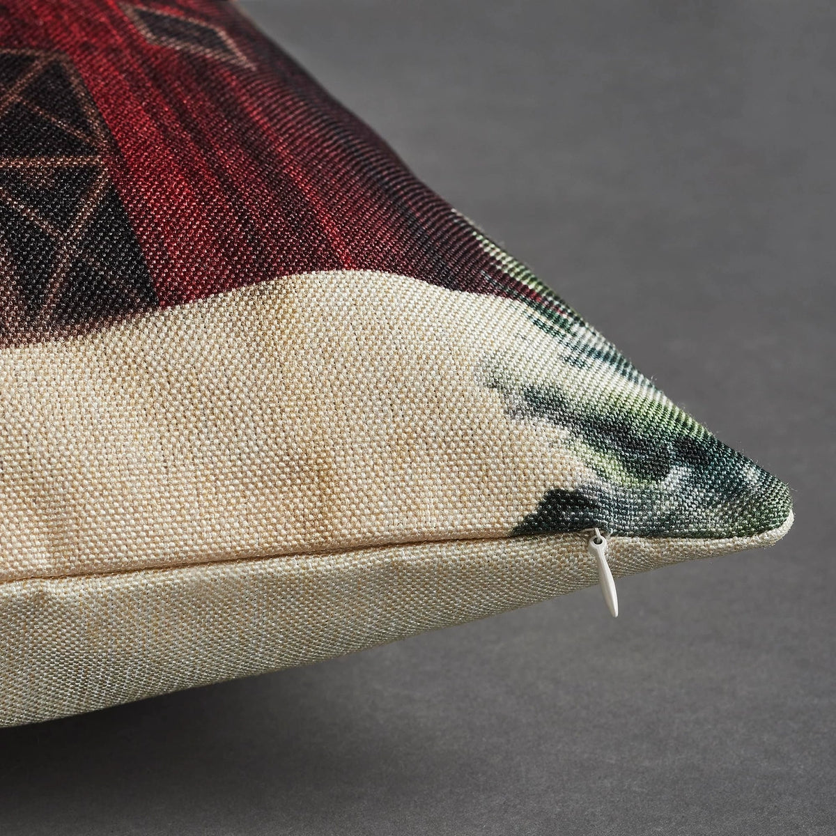 Close-up of the red barn pillow cover showing woven fabric, snowy evergreen print, and a concealed zipper along the edge.