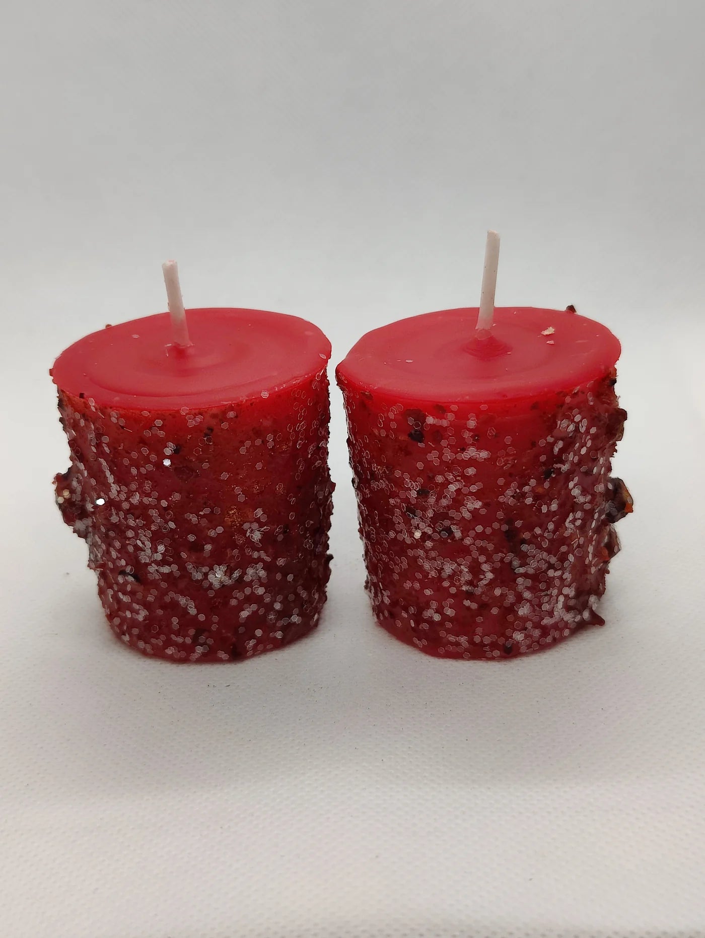 Two red textured candles on a white background