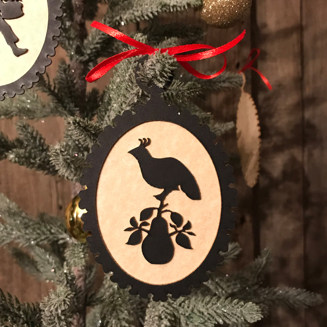 Decorative ornament with a rooster silhouette on a Christmas tree.