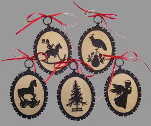 A set of five black silhouette ornaments with red ribbons, featuring various designs including an animal, a bird, a Christmas tree, and two figures.