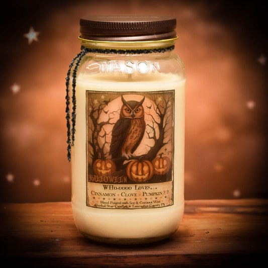 A mason jar candle with a label that has an owl, pumpkins, and text, placed on a wooden surface with a warm light background.
