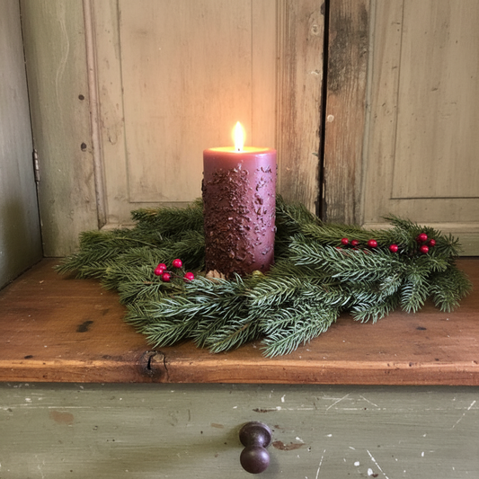 Purple candle on a green wreath with berries on a wooden surface.