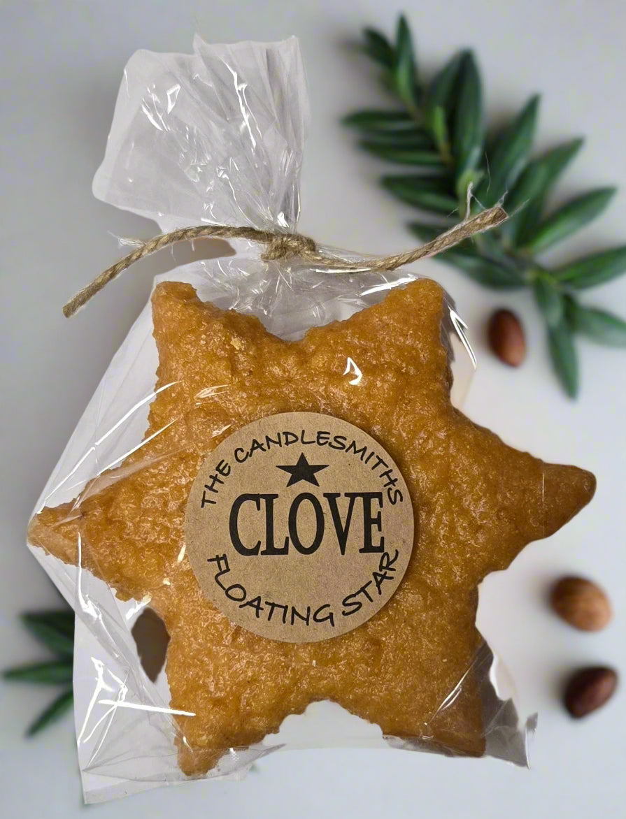 A star-shaped floating candle with a natural clove scent, packaged in clear wrapping with a label that reads 'CLOVE FLOATING STAR'.