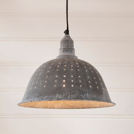 A weathered zinc pendant light with small holes and a ceiling plate, hanging against a white background.