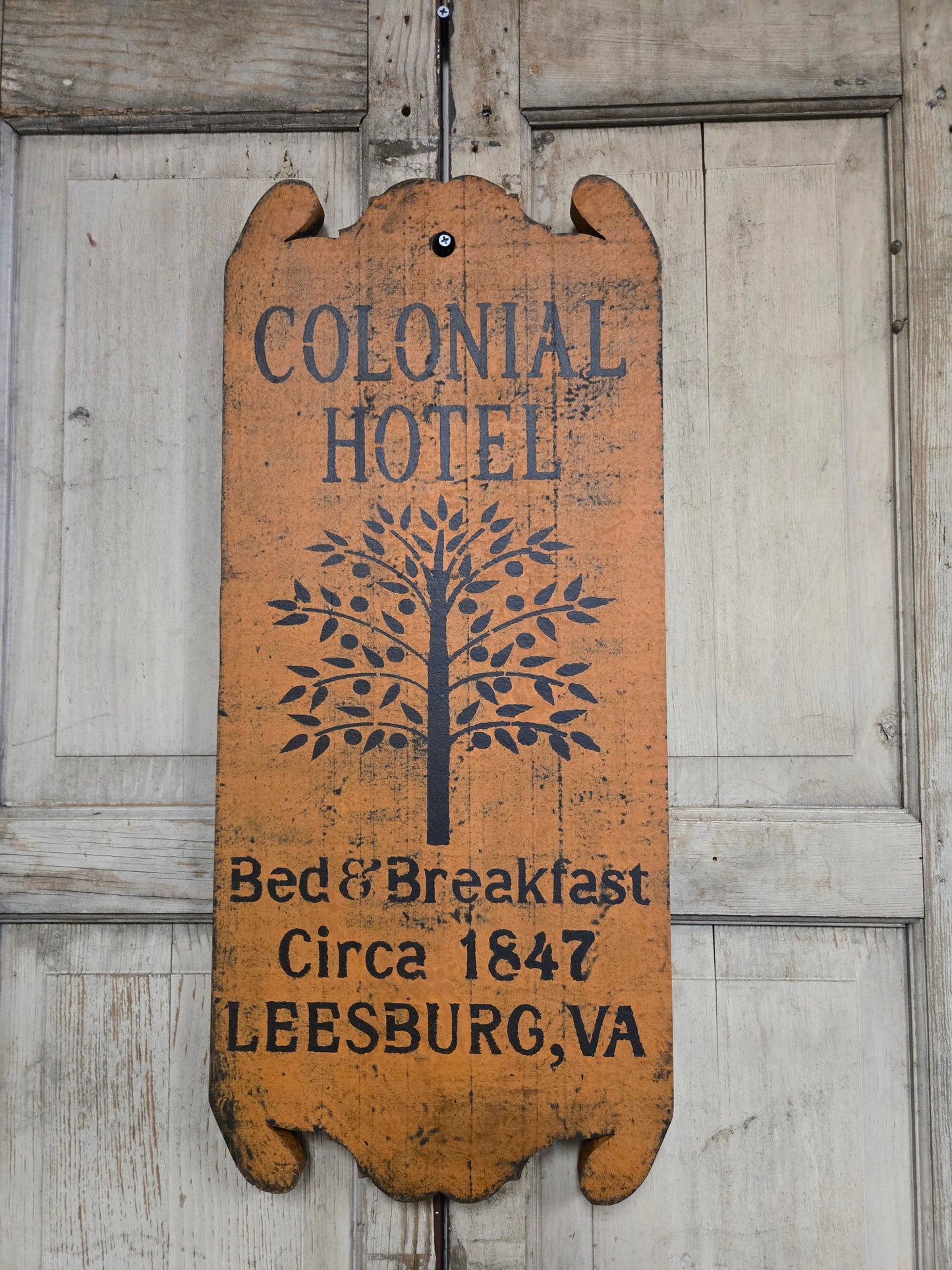 Vintage-style sign for Colonial Hotel on a wooden background