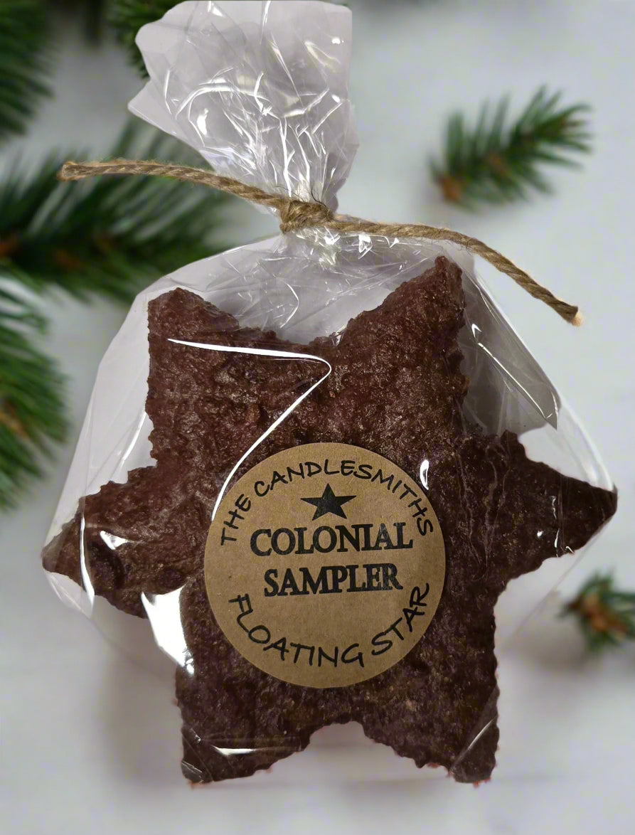 A brown floating candle designed in the shape of a large star, packaged in a clear plastic bag with a label reading 'Colonial Sampler Floating Star'.