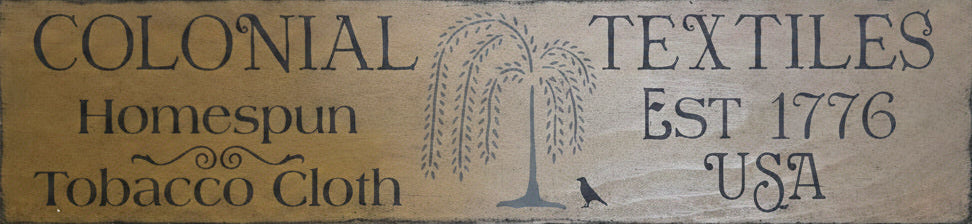 Wooden sign with 'Colonial Textiles' branding on a wooden background