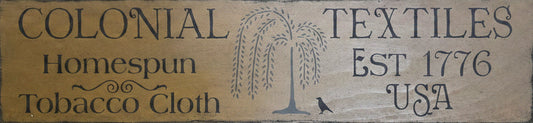 Wooden sign with 'Colonial Textiles' branding on a wooden background