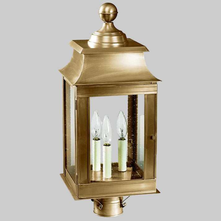 Decorative brass outdoor lantern with glass panels on a white background