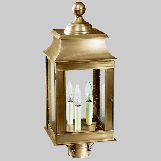 Decorative brass outdoor lantern with glass panels on a white background
