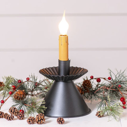 Black candle holder with a lit yellow candle on a white background with decorative elements.