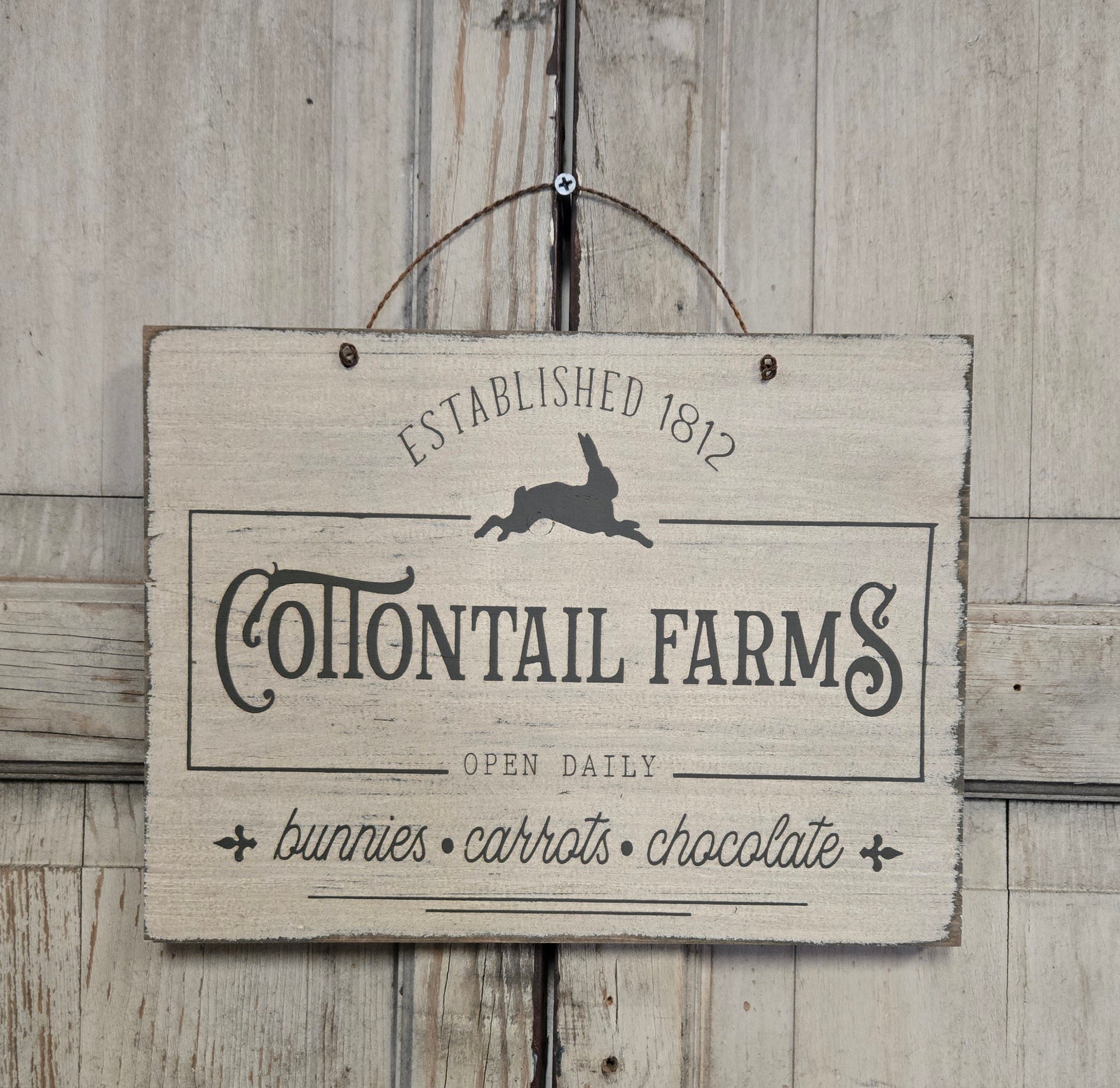 Wooden sign with 'Cottontail Farms' text and rabbit illustration on a wooden background
