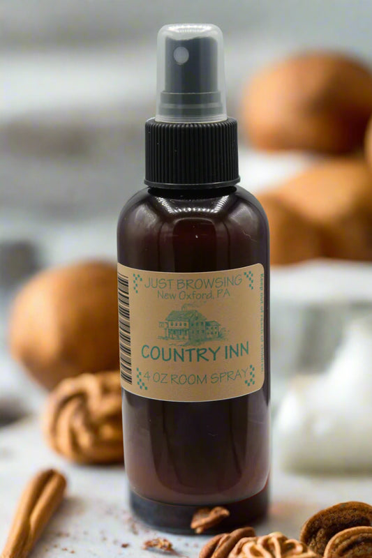 A 4oz bottle of Country Inn room spray with a mist spray top, labeled as such and with a brown liquid visible.