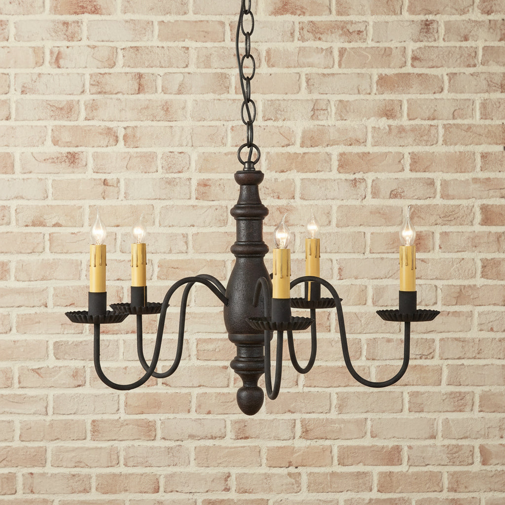 Black chandelier with six candle-style lights on a brick background