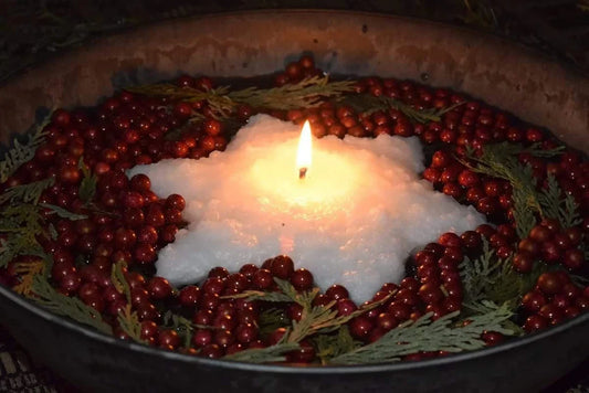 Star-shaped candle surrounded by red berries and greenery in a dark setting