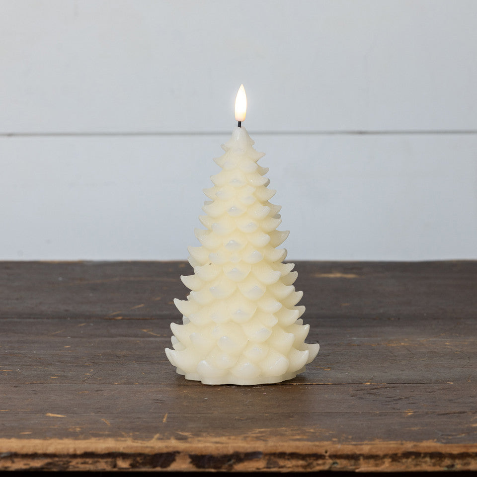 Decorative candle shaped like a Christmas tree on a wooden surface with a light gray background