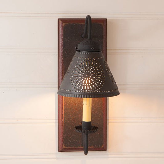 Decorative wall sconce with a black metal shade on a wooden bracket against a neutral wall.