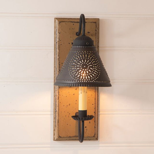 Decorative wall sconce with rustic design on a wooden panel.