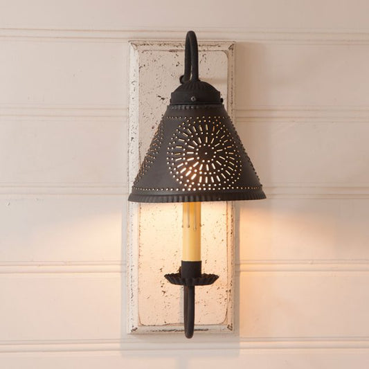 Decorative wall sconce with black metal shade and white wooden frame on a neutral wall.