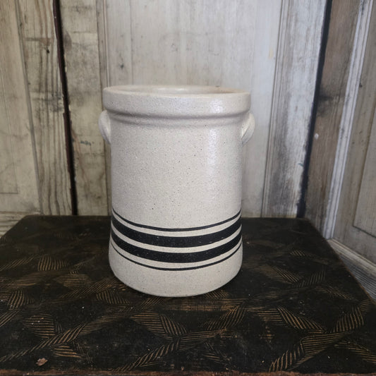 White ceramic vase with black stripes on a textured surface