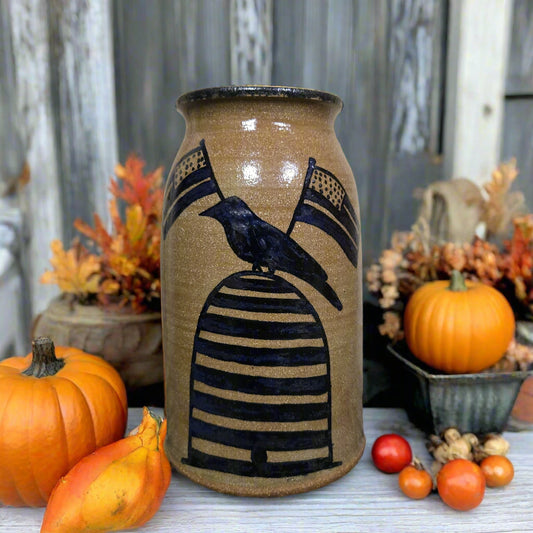 Ceramic vase with crow design surrounded by pumpkins and autumn decorations on a rustic background