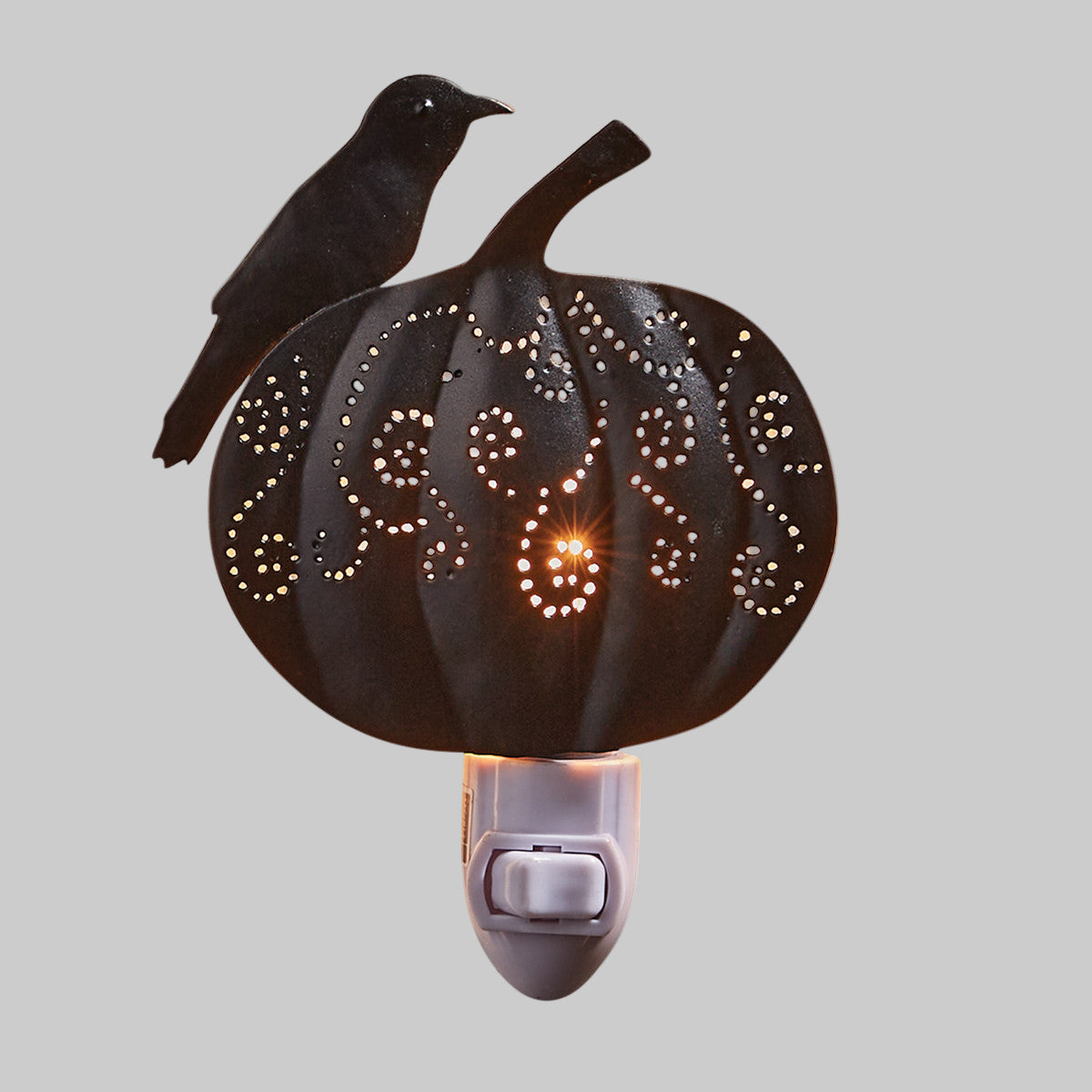 A night light featuring a carved pumpkin with a crow perched on top, with a warm glow emitting from the pumpkin.