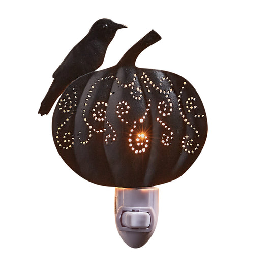 A night light featuring a carved pumpkin with a crow perched on top, with a warm glow emitting from the pumpkin.