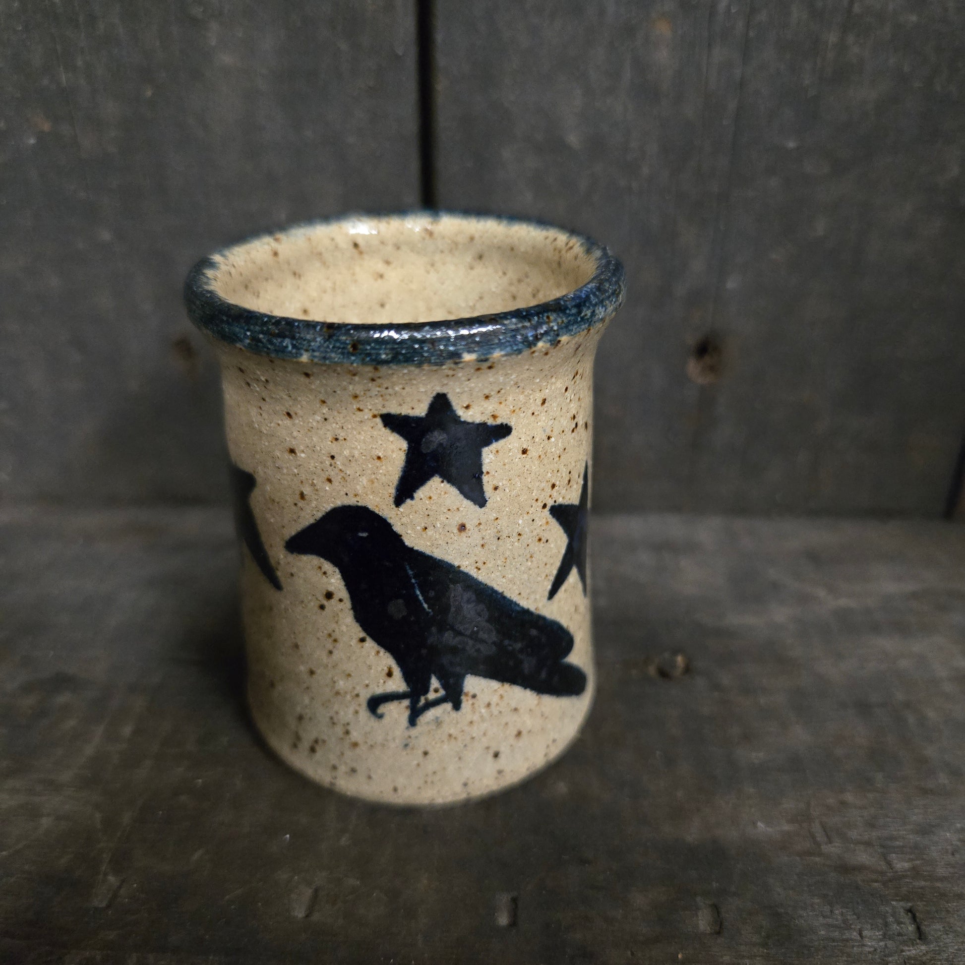 Ceramic cup with black star and bird design on a textured surface