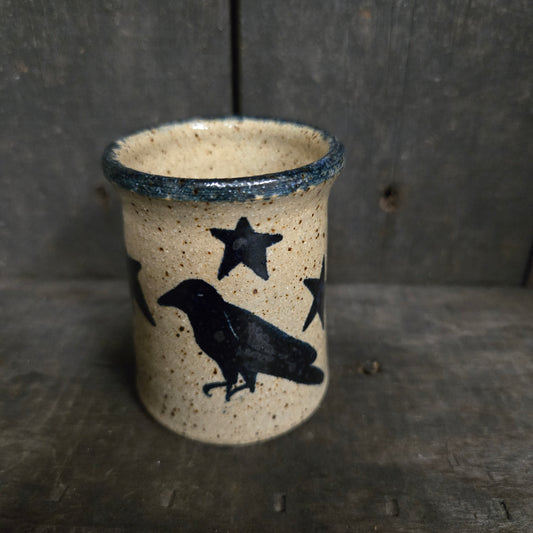 Ceramic cup with black star and bird design on a textured surface