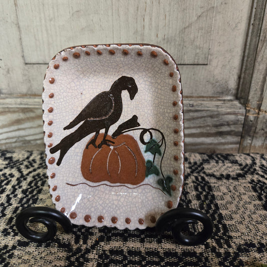 Small rectangular redware plate featuring a crow sitting on a pumpkin on the vine